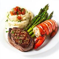 A gourmet surf and turf platter featuring a perfectly seared filet mignon and a buttery lobster tail, served with roasted garlic mashed potatoes and steamed asparagus. A luxurious meal. Isolated on photo