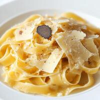 A plate of tagliatelle al tartufo bianco, featuring long, flat egg noodles, tossed in a rich and creamy sauce, made with butter, parmesan cheese, and shaved white truffles, resulting in a luxurious photo