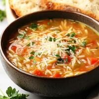 A close-up of a warm and comforting orzo soup, a hearty Italian soup with orzo pasta, vegetables, and chicken broth, simmered until thick and flavorful, garnished with grated parmesan cheese and fresh photo