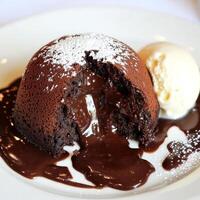 A close-up of a chocolate lava cake, a decadent and warm French dessert, with a dark chocolate cake shell, encasing a gooey and molten chocolate center, that oozes out when sliced open, served warm photo