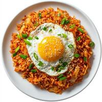 A plate of spicy kimchi fried rice, topped with a sunny-side-up egg and garnished with sesame seeds and sliced green onions. The dish has a vibrant red-orange hue, bursting with bold flavors. Isolated photo