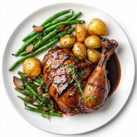A plate of duck confit, duck leg preserved and slow-cooked in its own fat, resulting in tender and flavorful meat with crispy skin, served with roasted potatoes and a side of green beans, garnished photo