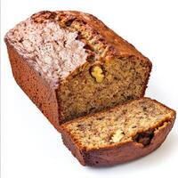 A rustic loaf of banana bread with a golden brown crust, sliced to reveal its moist, fluffy interior, with visible banana chunks and walnuts. Isolated on clean white background photo