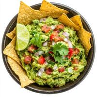 A bowl of fresh guacamole made with mashed avocados, diced tomatoes, onions, cilantro, and a squeeze of lime juice. The vibrant green dip is served with crispy tortilla chips for a classic Mexican photo