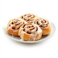 A plate of soft, golden-brown cinnamon rolls, generously coated with creamy vanilla icing that drips down the swirls of warm, spiced dough. The perfect sweet breakfast treat. Isolated on clean white background photo