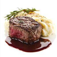 A perfectly seared filet mignon, cooked to a tender medium-rare, with a side of creamy mashed potatoes and a drizzle of red wine reduction sauce. A gourmet steakhouse dish. Isolated on clean white background photo