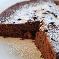 A close-up of a sweet and delicate torta caprese dessert, a flourless Italian chocolate cake, originating from the island of Capri, made with dark chocolate, ground almonds, butter, eggs, and sugar, resulting in a dense and fudgy cake with a slightly crus photo