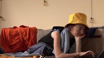 Young Woman in Yellow Hat Working on Laptop at Home while creating a digital wardrobe embracing simplicity mindful lifestyle and letting go of things that no longer bring joy video