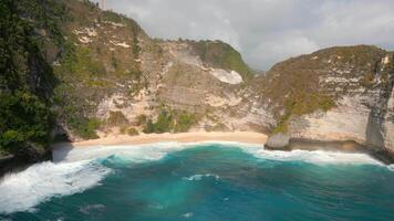 Aerial view of remote tropical beach with turquoise sea and dramatic cliffs on Nusa Penida, Bali, Indonesia. Ideal for travel, nature, summer, and scenic destination themes. video