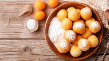 Doughnuts with powdered sugar and apricots in wooden bowl on table, close-up view photo