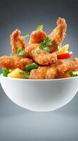 Fried chicken bites with parsley and peppers in a bowl, gray background. Food photography photo