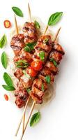 Grilled beef skewers with noodles, tomatoes, and basil on a white surface. Possible use menu photo