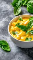Mango dessert with basil in a bowl for a gourmet menu, against a textured background photo
