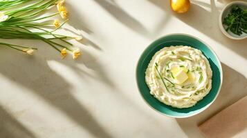 Mashed potatoes with butter and chives on a table with flowers. Food blog or recipe photo