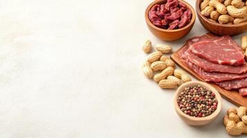 Meat jerky and nuts in bowls are ready to eat. Background is blurred, with neutral color. Stock photo