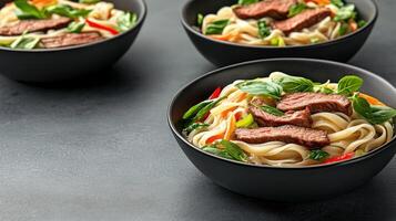Noodles with steak served in bowls for dinner in a home with dark countertop background photo