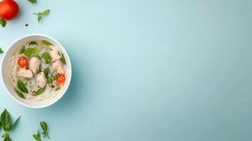 Overhead shot chicken noodle soup with basil leaves and tomatoes on blue background photo