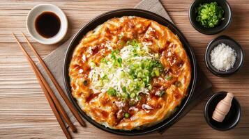 Overhead shot of okonomiyaki pancake topped with cabbage and scallions with sauce and chopsticks photo