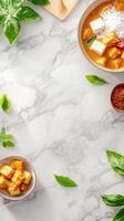 Overhead shot of tofu in curry on marble, with herbs and spices in the background for cooking recipe photo