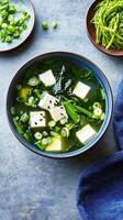 Overhead view of a bowl of miso soup, with tofu, scallions, and seaweed. Use for food blogs photo