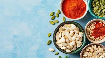 Overhead view of spices and pumpkin seeds in bowls on a light blue surface for food photography photo