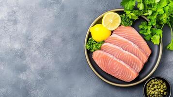 Raw salmon fillet steaks on a plate with lemon and parsley, served on a textured grey background photo