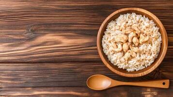Rice bowl with cashews and a spoon on a wooden background for healthy eating and balanced diet photo