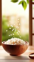 Rice pouring into a bowl on a wooden table in front of a window with blurred green leaves background photo