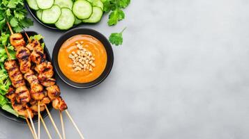 Satay chicken skewers served with peanut sauce, cucumber, and herbs for delicious street food photo