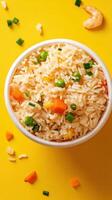 Shrimp fried rice in a bowl with spring onion and vegetables over a yellow background for takeout menus photo