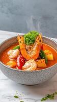 Shrimp curry in a bowl on a marble table, with vegetables and steam in the background. Food photography photo