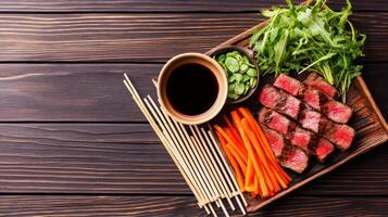 Sliced beef steak, served with arugula, carrots, and sauce on a wooden tray for culinary use photo