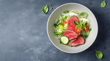 Sliced beef on noodles with vegetables in bowl on table. Menu item for a restaurant photo