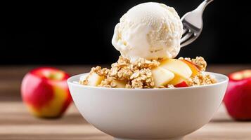 Spooning vanilla ice cream over apple crisp in a white bowl on wood table with a dark background photo