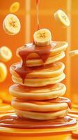 Stack of Pancakes with dripping syrup and flying banana slices on orange for breakfast menu photo