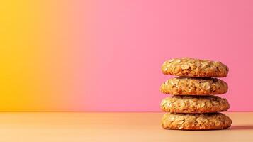 Stacked oatmeal cookies on table against gradient pink and yellow backdrop in studio, side view photo