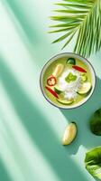 Tasty green curry with rice vegetables in a bowl on a bright table under palm leaves. For menu photo