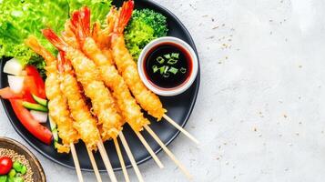 Tempura shrimp served with vegetables on a plate, sauce, and sesame seeds as background photo