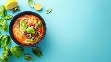 Top view of a noodle soup bowl with fresh basil, and limes on a blue background. For healthy recipes photo