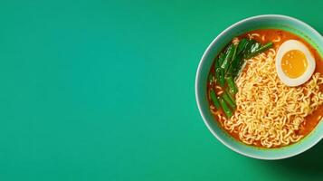 Top view of noodle bowl with egg and vegetables on green background for cookbook menu design photo