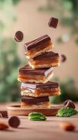 Tower of caramel squares with candies falling on table, plants in background, for dessert menu photo