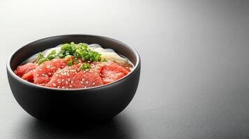 Tuna donburi with rice noodles and scallions served in a black bowl with a dark surface background for menu use photo