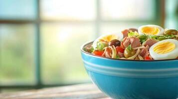 Tuna salad with eggs and olives in a bowl on a table. Breakfast or lunch on a sunny day photo