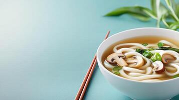 Udon noodle soup in bowl with mushroom, scallions, and broth on blue backdrop. Food photography photo