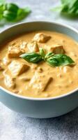 Vegan tofu curry served in a bowl with basil on a grey surface, use for food blogs and recipes photo