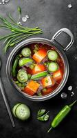 Vegan tomato soup with tofu and cucumber being served on a black table for meal photo