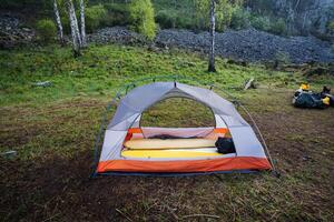 A serene camping scene beautifully showcases a cozy tent setup nestled within a lush green forest, embodying both adventure and tranquility, inviting everyone to explore the wonders of nature photo