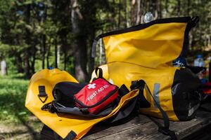 Inside a bright yellow bag, you will find a first aid kit placed conveniently on a sturdy wooden table, ensuring easy access during any emergencies or urgent situations that may arise photo