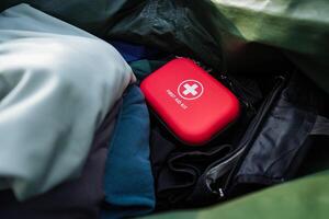 A Compact First Aid Kit is packed in a durable bag among clothing items, ensuring its easily accessible during emergencies while traveling or outdoor activities like hiking or camping photo
