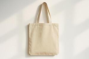 Blank beige canvas tote bag on light wall with soft shadows. Eco-friendly reusable bag mockup with copy space photo